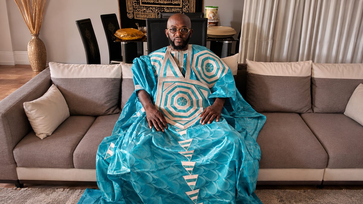 Marabout Djibril en boubou turquoise, assis dans son salon